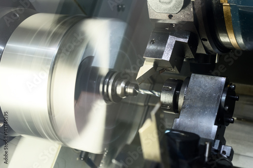 The CNC lathe processes the metal part.