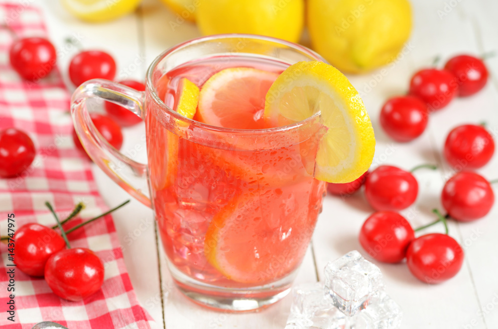 Fruit cherry ice tea with slice of lemon in mug and cherries Fruit cherry ice tea with slice of lemon in mug and cherries