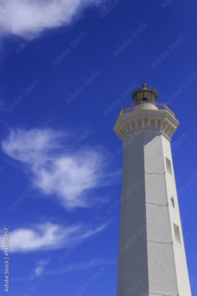White lighthouse on a blue sky with white clouds.It is located in the town of Torre Canne on the Adriatic sea coast of Apulia in Italy.