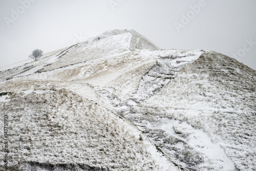 Beautiful Winter landscape image around Mam Tor countryside in Peak District England with lone hiker photo