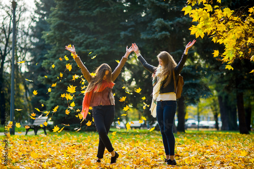 Two girls cheerfully spend time in the autumn park.