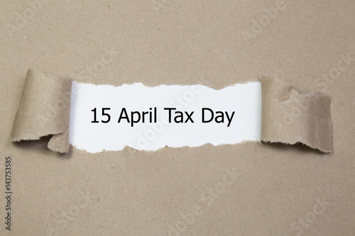 The word 15 april tax day appearing behind torn paper. 
