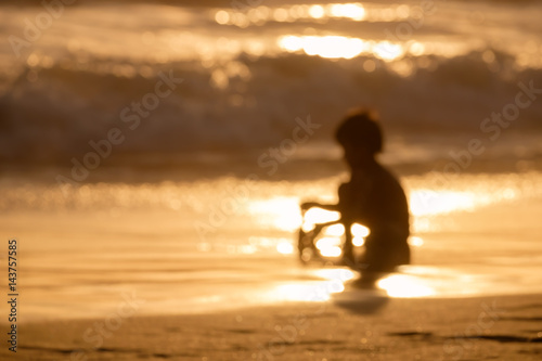 Blur kid playing sand on the beach during sunset abstract background.
