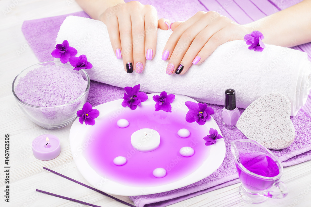 beautiful purple manicure with violet, candle and towel on the white wooden table. beautiful purple manicure with violet, candle and towel on the white wooden table.