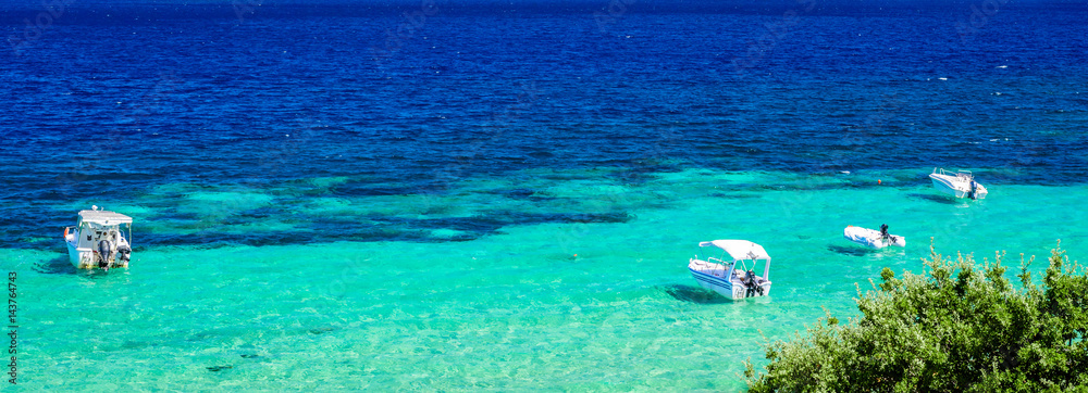 Beach at sunny day with clear blue sky, turquoise sea water and bouts. Photo from Megali Amos or the Big sandy beach, Ammouliani Island, Athos, Halkidiki, Northern Greece.