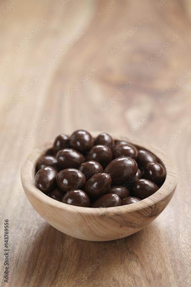 chocolate covered almonds in wood bowl on table, with copy space chocolate covered almonds in wood bowl on table, with copy space