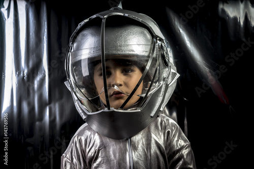 Fotografie Science, Boy playing to be an astronaut with a space helmet and silver suit on m