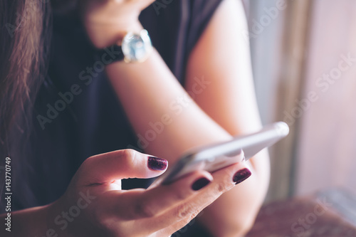 A woman holding and using smart phone in modern cafe
