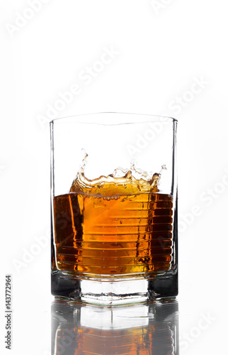 A glass of whiskey in which poured on a white background.