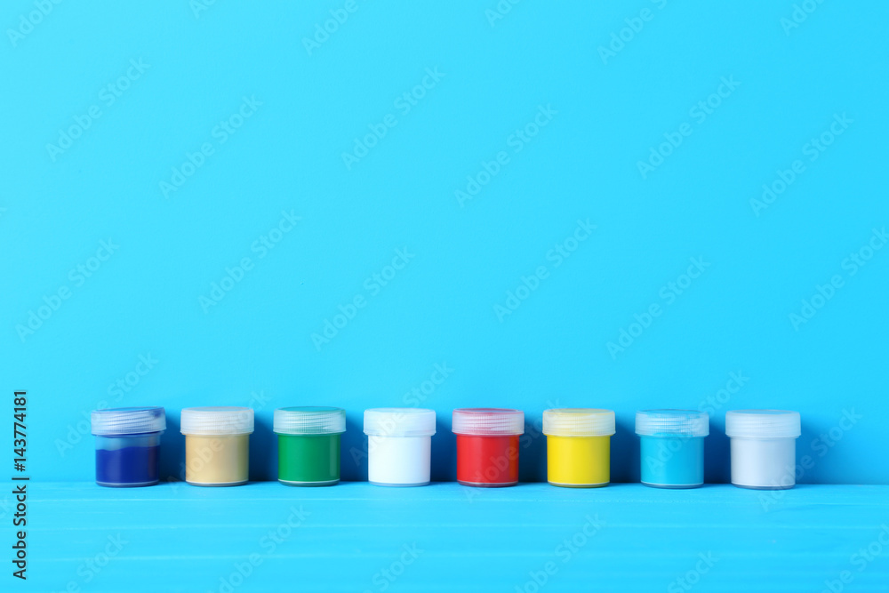 Colorful paints in bottles on blue background Colorful paints in bottles on blue background