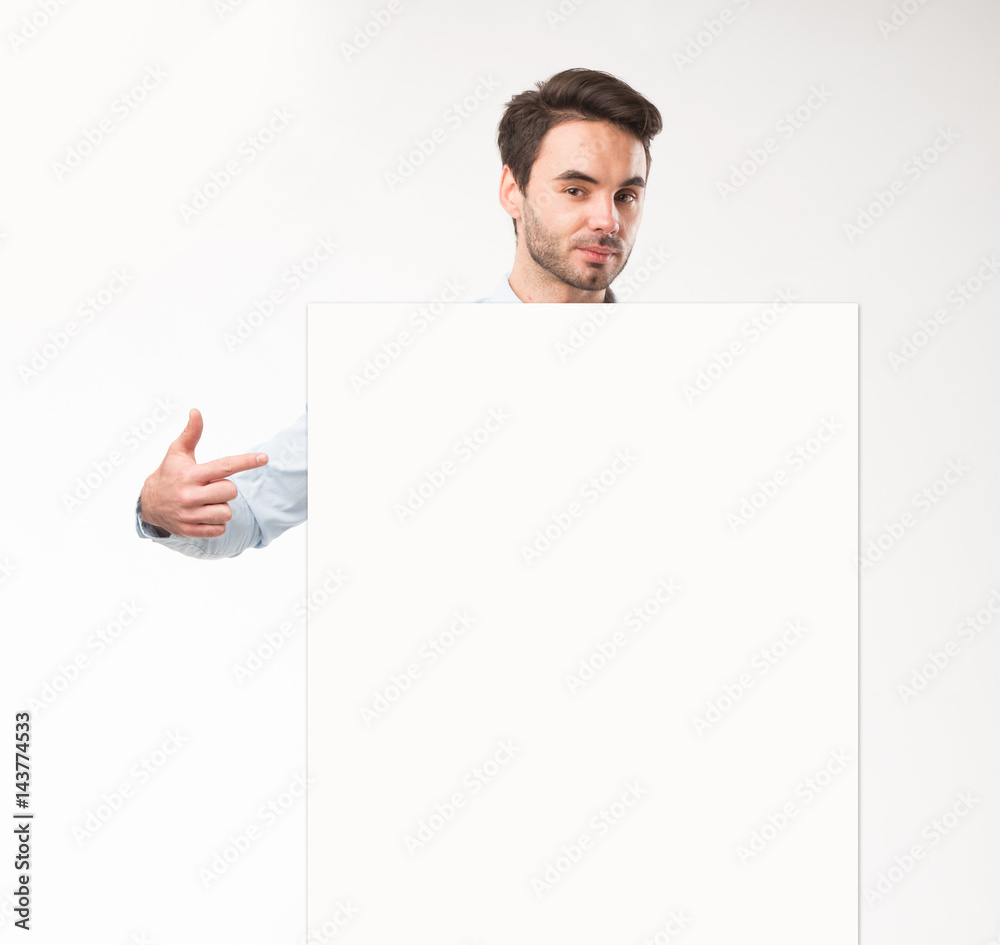 Young happy man showing presentation, pointing on placard over gray background Young happy man showing presentation, pointing on placard over gray background
