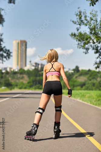 Fit, sporty and athletic young woman. Beautiful girl rollerblading on skates in a sportswear.