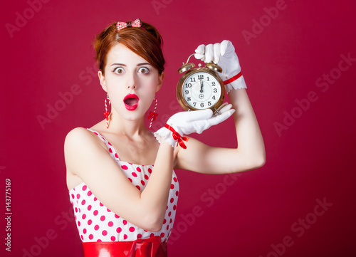 photo of beautiful young woman in vintage dotted dress with alarm clock on the wonderful burgundy background