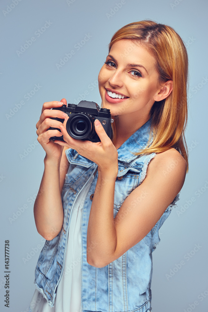 Smiling blond female holds compact digital photo camera. Smiling blond female holds compact digital photo camera.