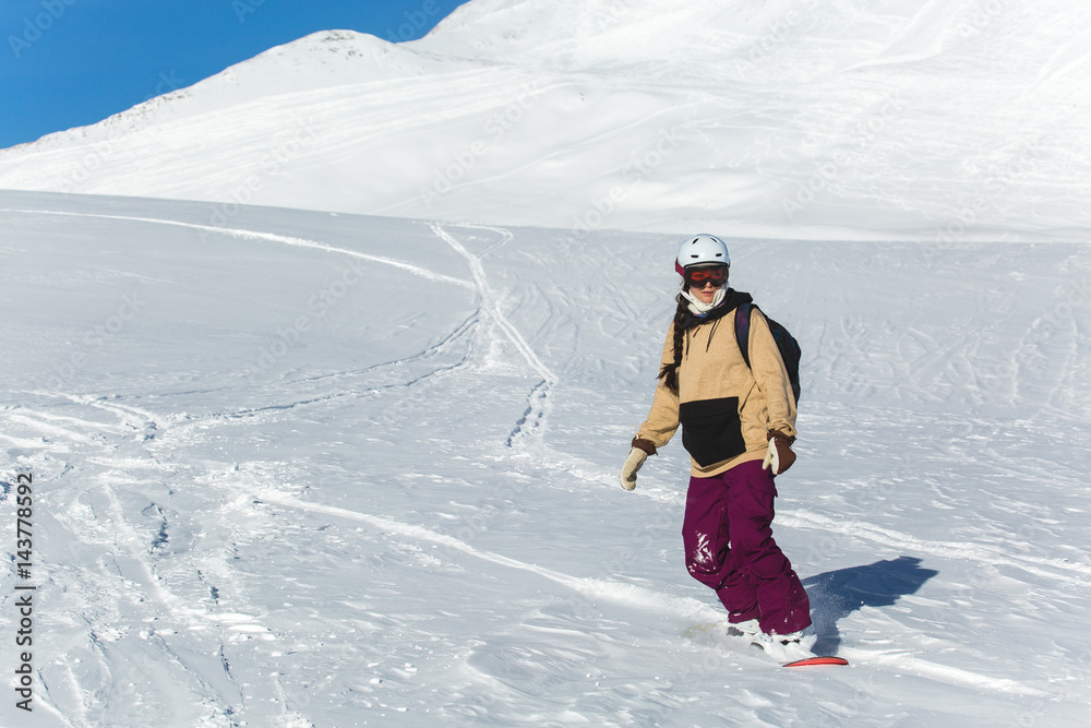 women snowboarder snowboarding on fresh white snow with ski slope on Sunny winter day