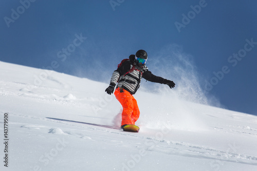  snowboarder snowboarding on fresh white snow with ski slope on Sunny winter day