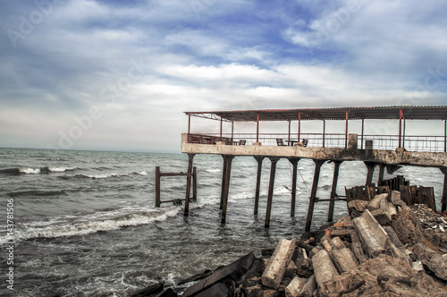 Beautiful surreal landscape of abandoned house and ladder on rocky seashore at sunset time. Cloudy weather. Caspian Sea  Azerbaijan 