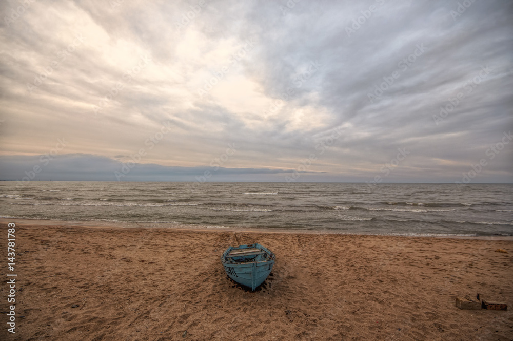 Beautiful landscape of Boat on the beach in cloudy weather. Vintage Boat in the seashore. Azerbaijan Caspian Sea Novkhani Beautiful landscape of Boat on the beach in cloudy weather. Vintage Boat in the seashore. Azerbaijan Caspian Sea Novkhani