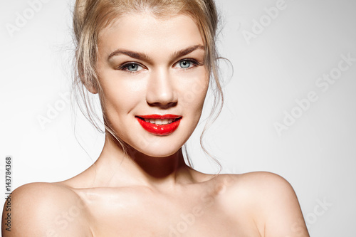 Close-up portrait of a young woman with bare shoulders with beautiful blue eyes and red lipstick