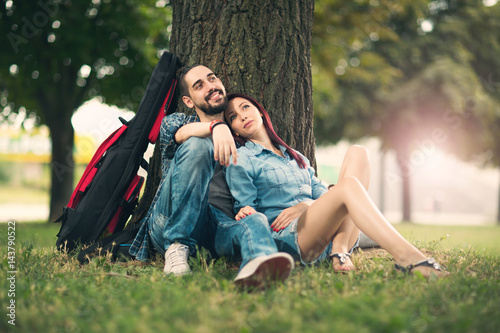 Loving couple holding each other sitting on a tree trunk on a romantic date in the park forest