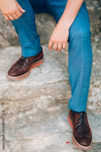 Brown shoes on male legs. The groom in a blue pants.