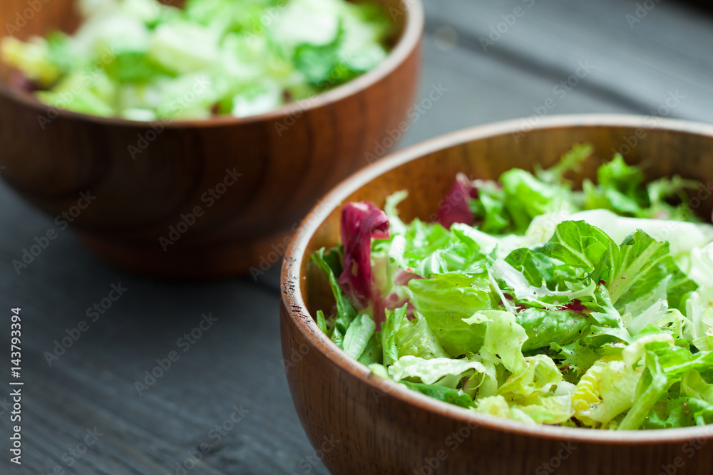 A dish of fresh salad frisse, Romano and radiccio with olive oil, salt and freshly ground percec in a wooden bowl A dish of fresh salad frisse, Romano and radiccio with olive oil, salt and freshly ground percec in a wooden bowl