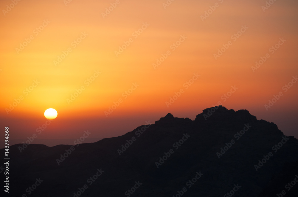 Natura e vita all'aria aperta: un tramonto infuocato sulla sagoma scura di una montagna Natura e vita all'aria aperta: un tramonto infuocato sulla sagoma scura di una montagna