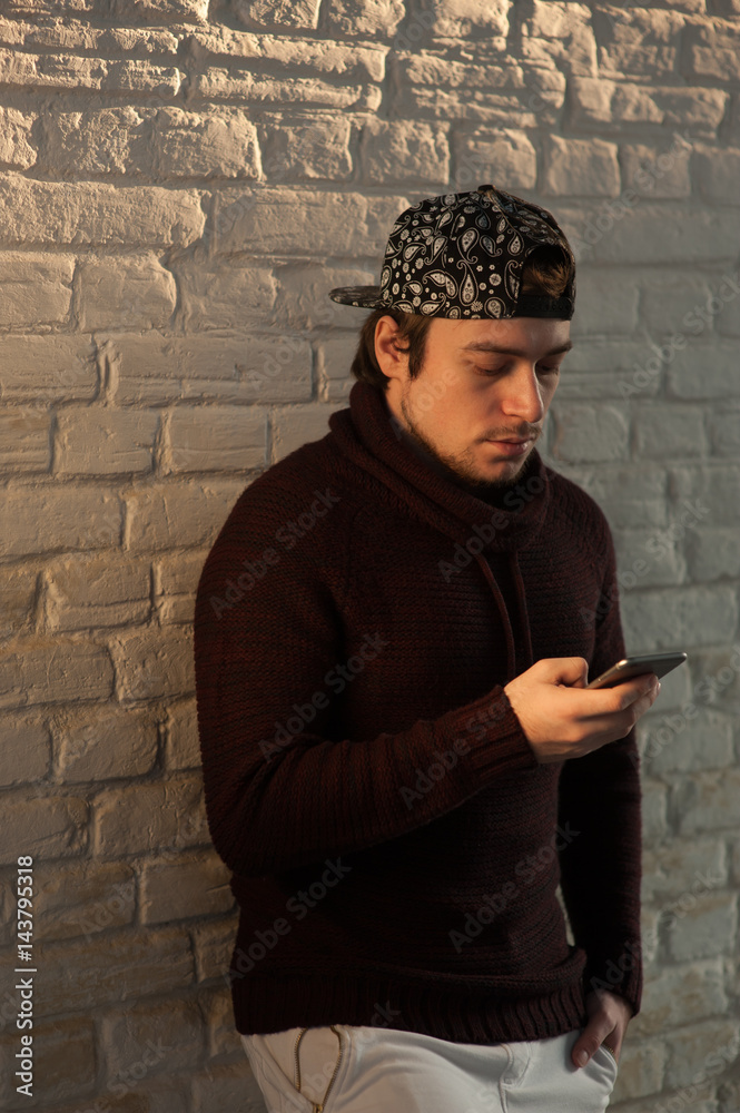 Obraz premium cute young man with smartphone on brick wall background