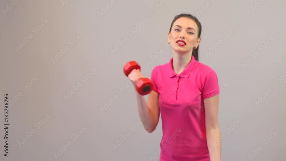 Attractive young woman in sports clothing, fitness and training biceps with dumbbells Attractive young woman in sports clothing, fitness and training biceps with dumbbells
