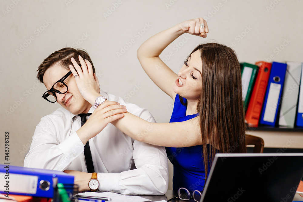 Young beautiful girl in blue dress tries to hit her colleague at work in the office Young beautiful girl in blue dress tries to hit her colleague at work in the office