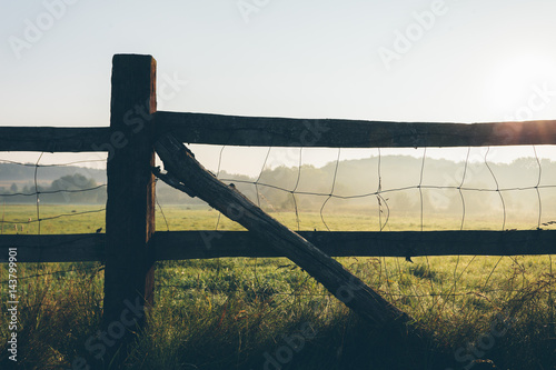 Old wooden rural fence on the field early in the morning