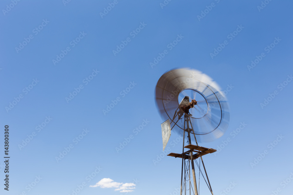 Close up wide angle image of a windmill / windpomp with spinning blades, pumping water in the Tankwa Karoo in South Africa on a hot summersday