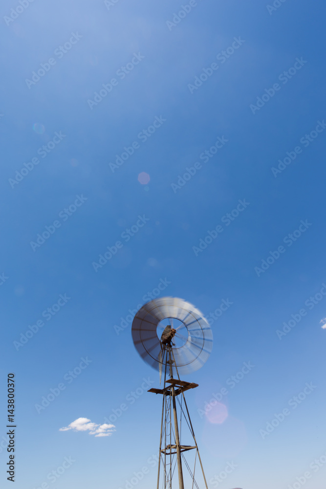 Close up wide angle image of a windmill / windpomp with spinning blades, pumping water in the Tankwa Karoo in South Africa on a hot summersday Close up wide angle image of a windmill / windpomp with spinning blades, pumping water in the Tankwa Karoo in South Africa on a hot summersday