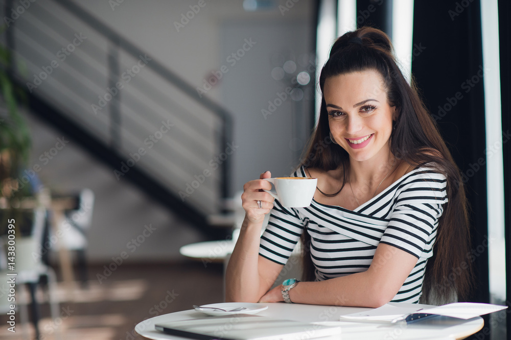 A close-up portrait of a woman with perfect smile holding a cup of cappuccino or coffee. White teeth and makeup. A close-up portrait of a woman with perfect smile holding a cup of cappuccino or coffee. White teeth and makeup.