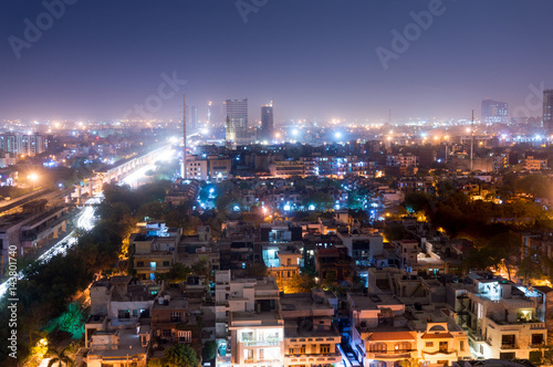 Noida cityscape at night with houses  office  skyscrapers  streets and metro rails visible. Lots of construction is visible as well showing the development