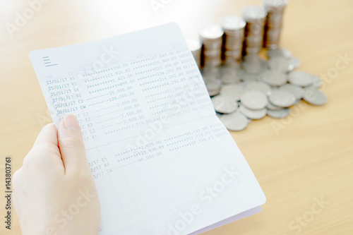 Woman hold passbook on hand, coins background