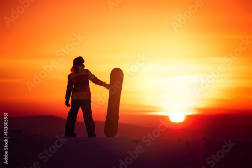 Fototapeta Naklejka Na Ścianę i Meble -  Woman snowboarder silhouette on sunset backdrop