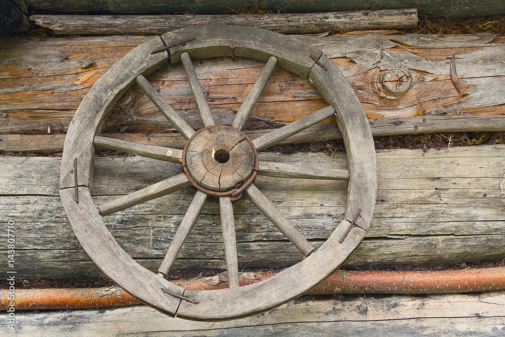 Wooden wheel from an ancient cart hanging on the wall of the hut