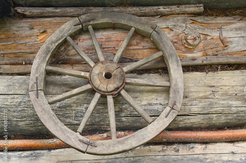 Wooden wheel from an ancient cart hanging on the wall of the hut © DmyTo