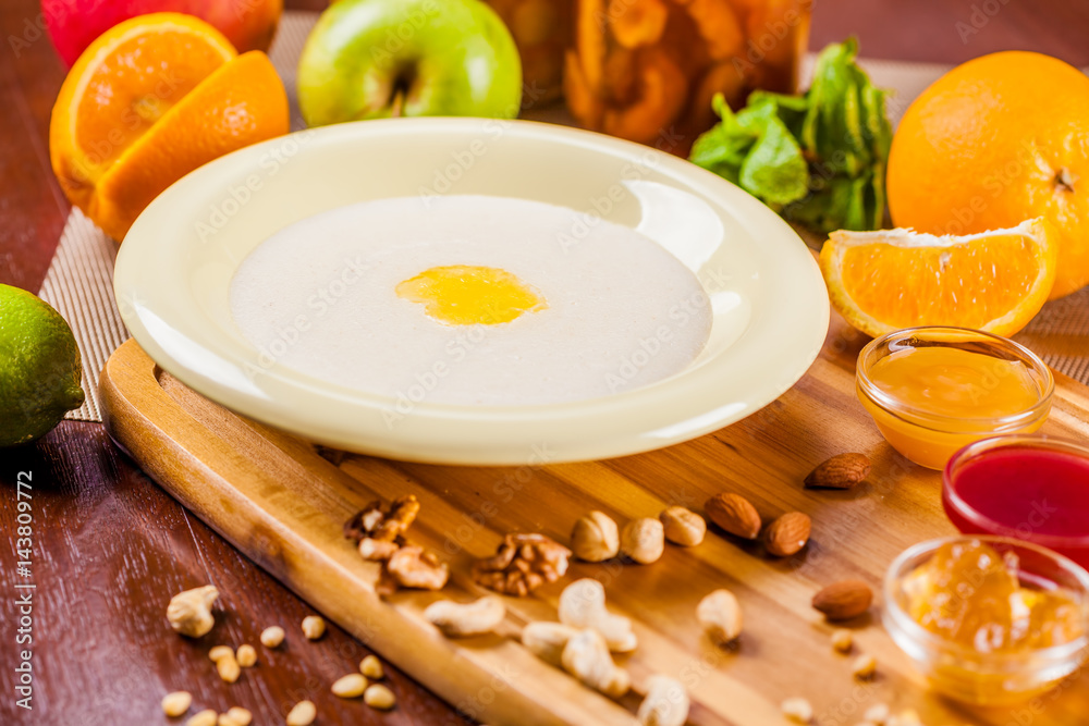 Semolina porridge with nuts, jam and fruits on wooden board Semolina porridge with nuts, jam and fruits on wooden board