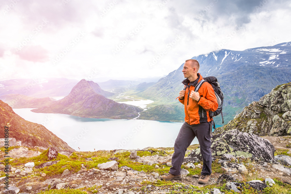 Obraz premium Young man hiking on Besseggen. Happy guy enjoy beautiful lake and good weather in Norway. Toning picture