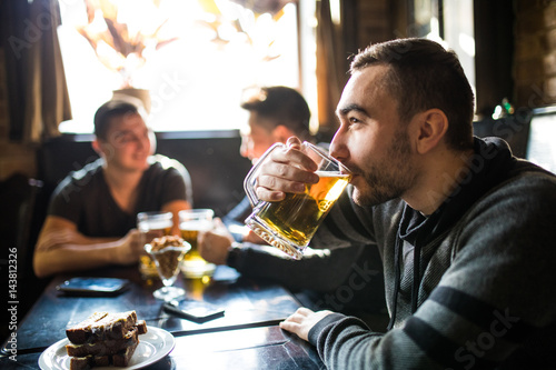 Man drink beer in front of to discussing drinking friends in pub. Friends in pub.