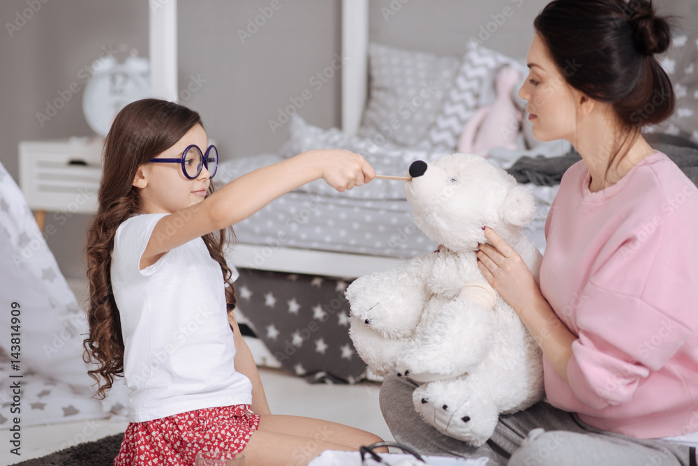 Caring little kid enjoying treating toys with mother at home Caring little kid enjoying treating toys with mother at home