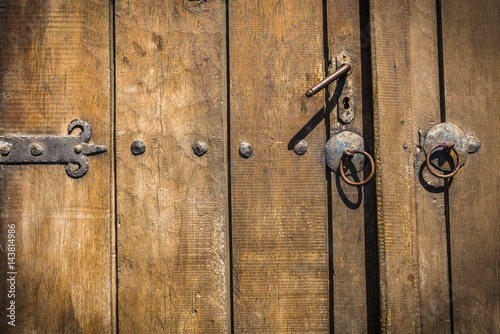 Detail of an old door handle. Rusting lock on an traditional door with paint peeling. Wooden background.