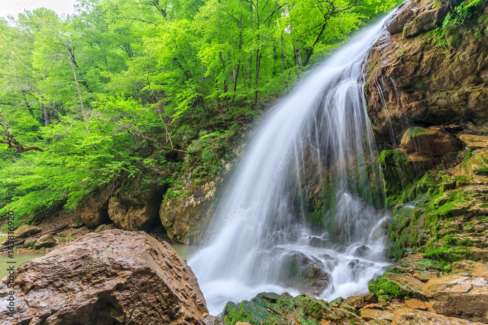 Beautiful scenic landscape of Rufabgo waterfall in green Caucasus mountain forest at springtime