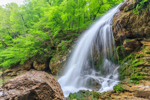 Beautiful scenic landscape of Rufabgo waterfall in green Caucasus mountain forest at springtime