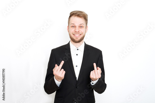 Cuadro en lienzo Young attractive man in a black suit showing middle finger on a white background