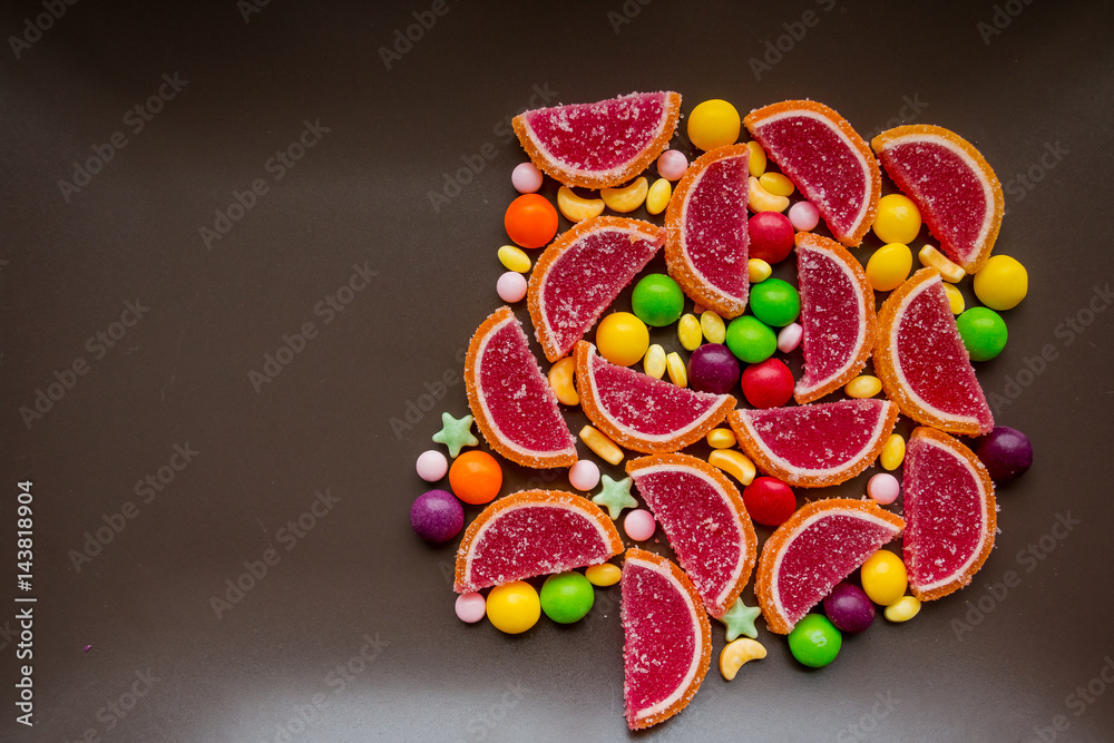 Closeup of the pile of colorful sweet bonbons. Colored sweets from marmalade in the form of slices of citrus fruits .Scattered dragees of different colors. 