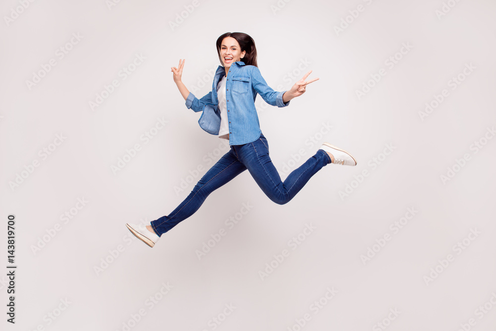 Excited happy pretty  girl in casual jeans clothes high jump with raised hands and legs, on white background