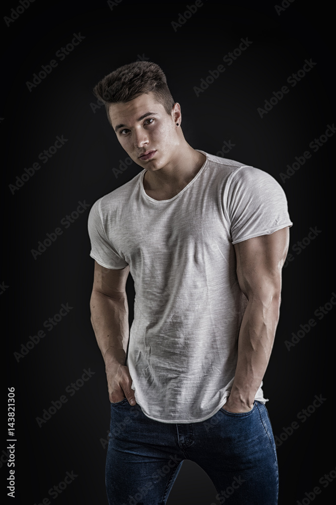 Handsome young muscular man looking at camera in studio shot over neutral background Handsome young muscular man looking at camera in studio shot over neutral background